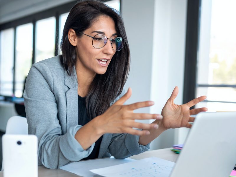 onfident business woman looking and speaking through the webcam while making a video conference